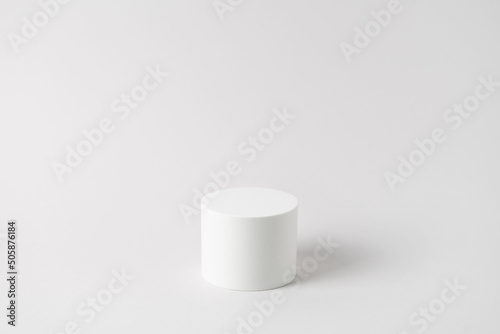 Empty white podium on light grey background. Minimal mockup. Round showcase for cosmetic product advertising. Abstract display or stage. Spa and beauty concept. Front view. Copy space.