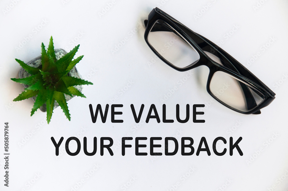 Top view of text with reading glasses and potted plant on white background - We value your feedback. Top view of text with reading glasses and potted plant on white background - We value your feedback.