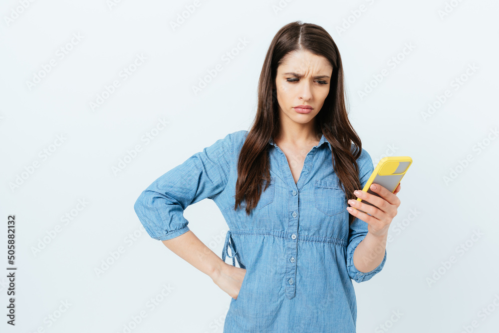 Annoyed young brunette woman looking at her smartphone Annoyed young brunette woman looking at her smartphone