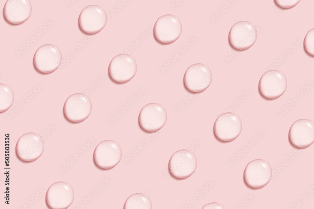 Pattern made of hyaluronic acid serum drops on pink background. Pattern made of hyaluronic acid serum drops on pink background.