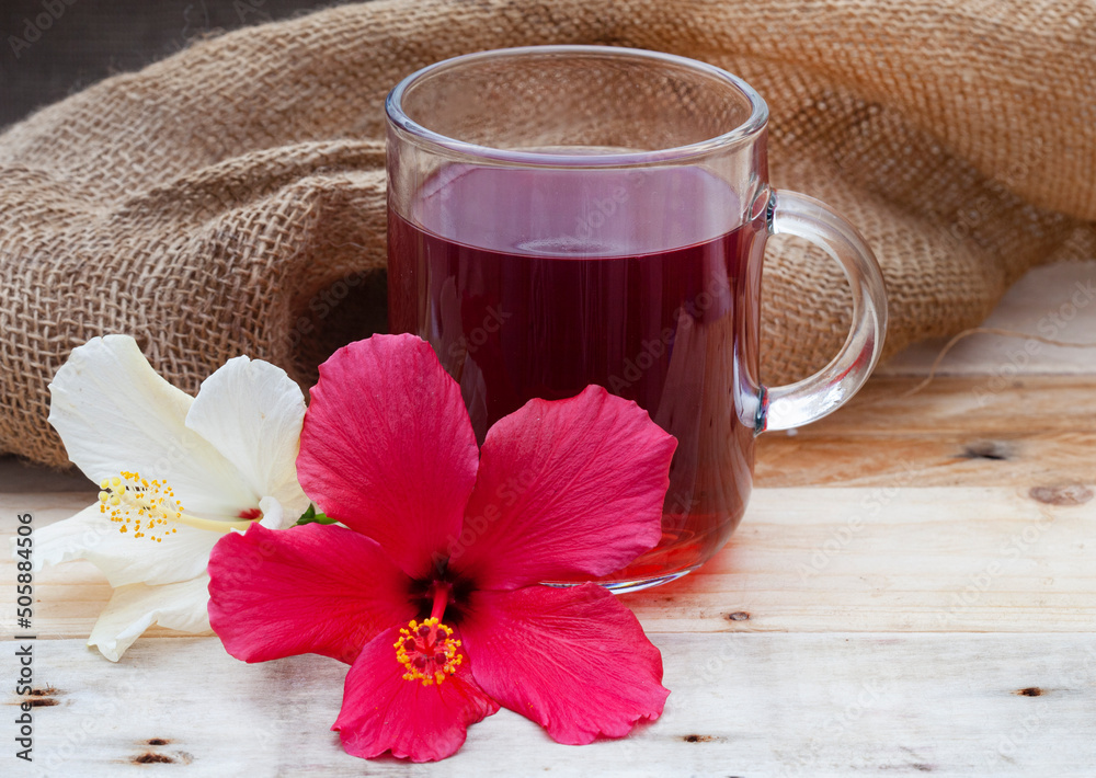 Bright and flavorful hibiscus tea in a glass cup, with hibiscus flower and copy space Bright and flavorful hibiscus tea in a glass cup, with hibiscus flower and copy space