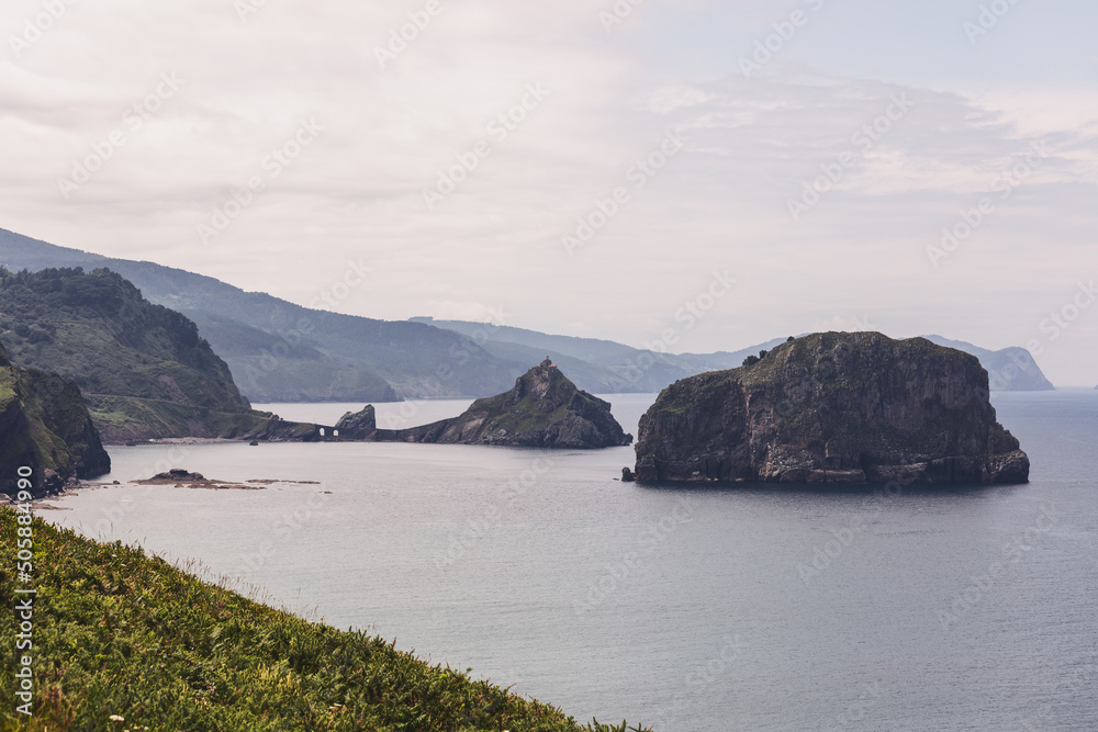 Deceptively calm waters of Bay of Biscay of Cantabrian Sea and the sparsely vegetated rocks and cliffs of Basque coastline and islands. Cape Matxitxako, Bermeo, Spain