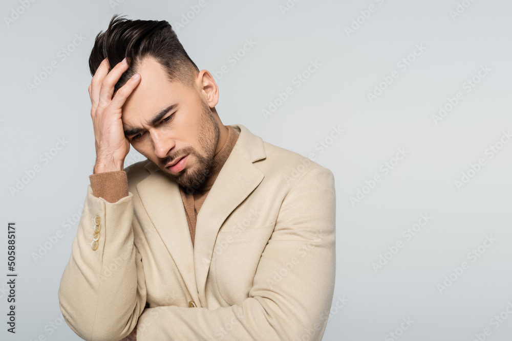 depressed critic in beige blazer touching head isolated on grey. depressed critic in beige blazer touching head isolated on grey.