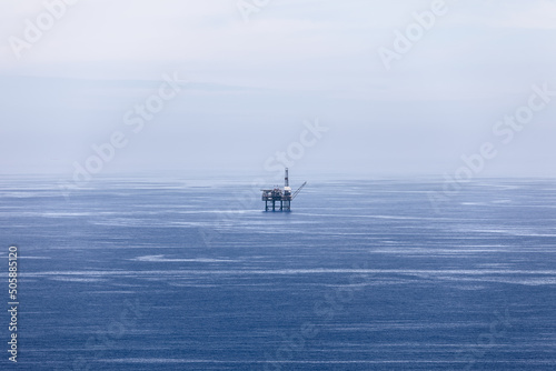 Blue waters of Bay of Biscay, covered with light ripples, merge with sky of almost same pale color and gas platform in the middle. Cape Matxitxako, Basque Country, Spain