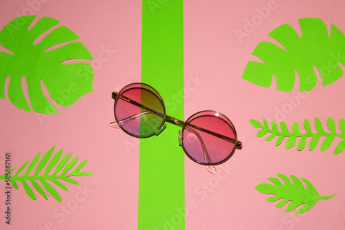 sunglasses on a pink-green background with green leaves, creative tropical design