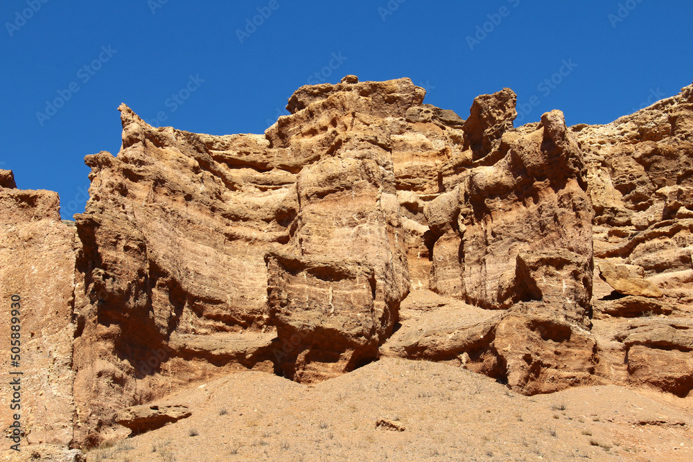 Beautiful relief sand-clay rocks and walls of the red Charyn canyon against a clear sky in sunny weather in summer