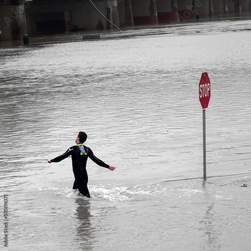 Man walking past stop sign of flooded street