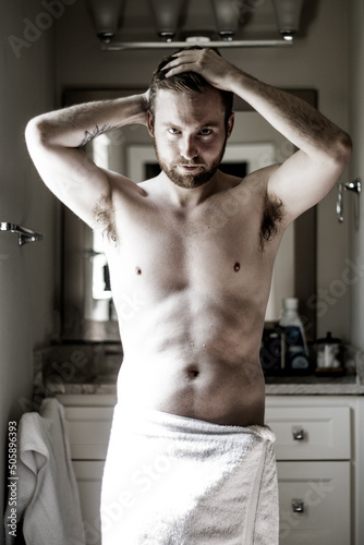Athletic man wearing towel in the bathroom sunlight