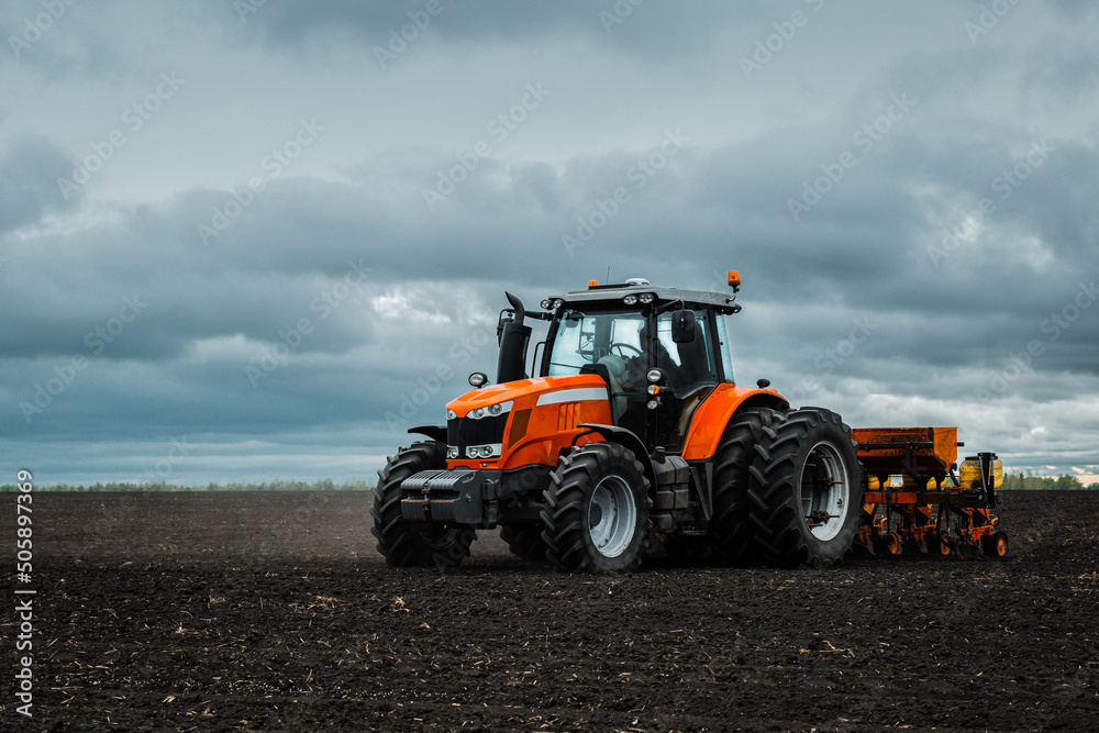 A tractor with a seed drill is engaged in planting corn. A tractor with a seed drill is engaged in planting corn.