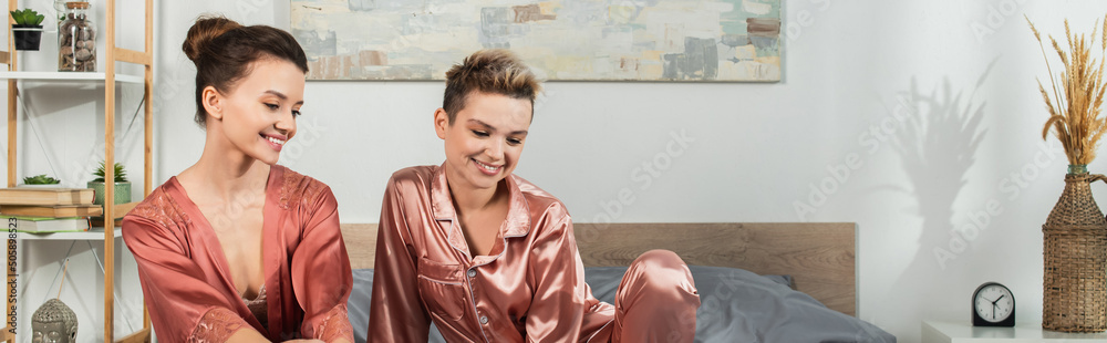 positive pansexual people in robe and satin pajamas smiling in bedroom, banner. positive pansexual people in robe and satin pajamas smiling in bedroom, banner.