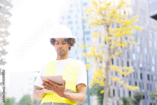 Young arhitect with helmet. Man using digital tablet photo