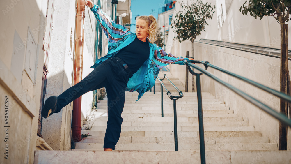 Professional Young Adult Woman in Casual Stylish Clothes Actively Breakdancing Hip Hop on the Street of an Old Town in a City. Scene Shot in an Urban Environment on an Quiet Small Town Stairs.