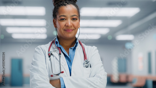 Medical Hospital Medium Portrait: African American Female Medical Doctor Takes of Glasses Looks Sincerely at Camera and Smiles. Successful Health Care Physician in White Lab Coat Ready to Save Lives