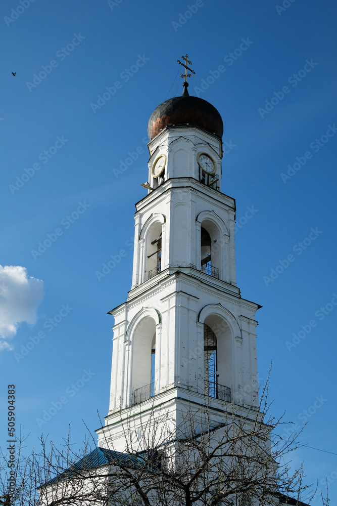 Orthodox bell tower chapel made of white stone against a clear blue sky