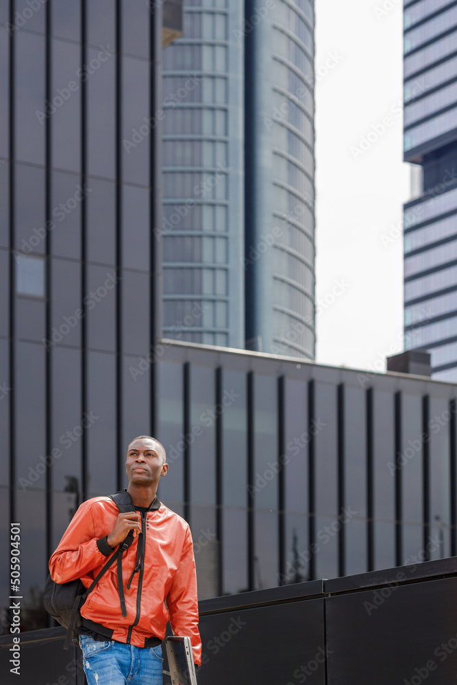 Confident black male student strolling near modern building in city Confident black male student strolling near modern building in city