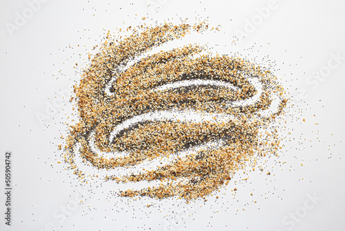 A scattered pile of Everything seasoning containing dried garlic, onion, poppy seeds, sesame seeds and salt on a white background. 
