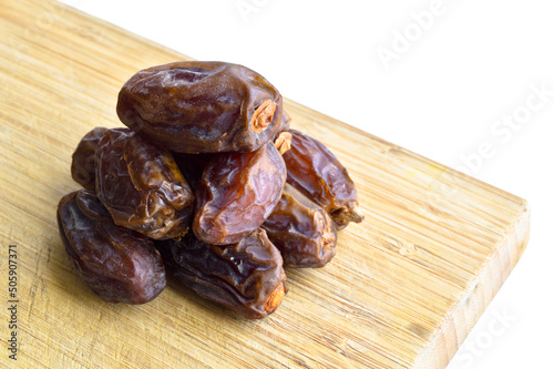 Organic fresh nutritious dried hurma dates medjool grains, on cutting board photo