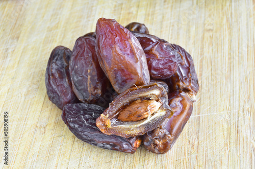 Organic fresh nutritious dried hurma dates medjool grains, on cutting board photo