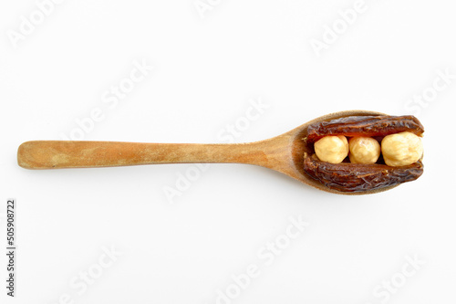 Dried hurma dates medjool grains, hazelnuts placed inside the date, on wooden spoon photo