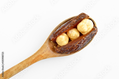 Dried hurma dates medjool grains, hazelnuts placed inside the date, on wooden spoon photo