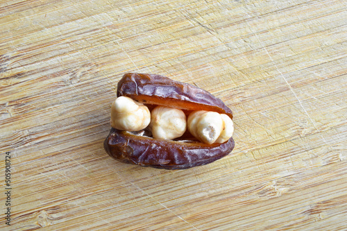 Dried hurma dates medjool grains, hazelnuts placed inside the date, on the cutting board photo