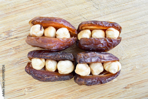Dried hurma dates medjool grains, hazelnuts placed inside the date, on the cutting board photo