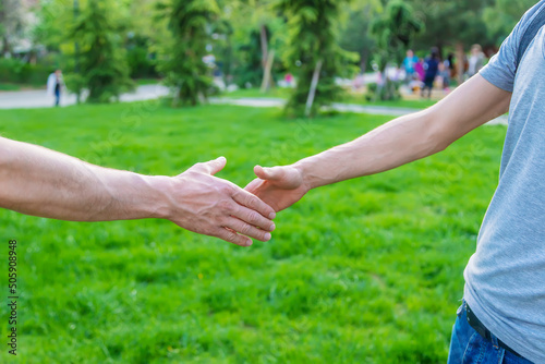 Handshake of men at a meeting in the park. Selective focus.