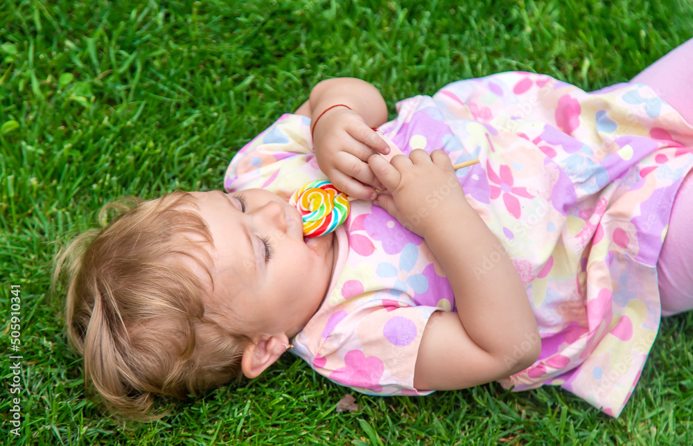 Baby eats a lollipop in the park. Selective focus. Baby eats a lollipop in the park. Selective focus.