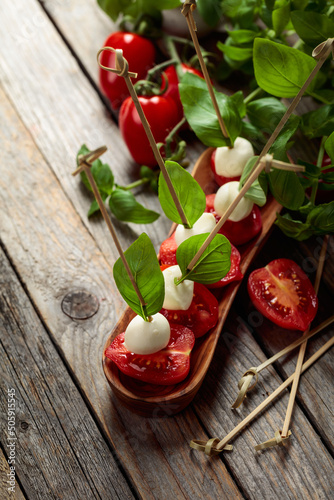 Mozzarella with basil and tomatoes on an old wooden table.