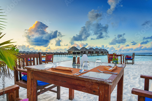 Fototapeta Naklejka Na Ścianę i Meble -  A table with glasses and cutlery on the luxury beach at sunset.