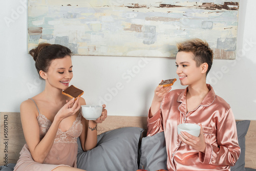 happy pangender people drinking tea with sweet toast bread for breakfast in bedroom. photo