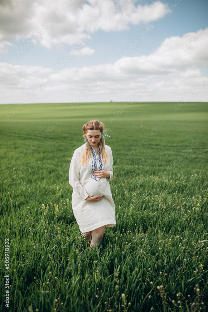 Young pregnant Ukrainian woman in ethnic national dress on a wheat field Young pregnant Ukrainian woman in ethnic national dress on a wheat field