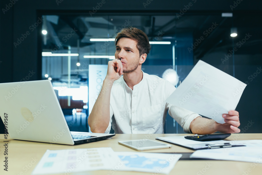 Upset freelancer works in the office, on paperwork, holds a contract disappointed and pensive