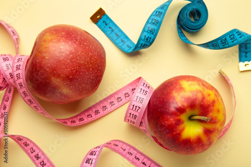 Diet concept with apples and measuring tapes, on a beige background.