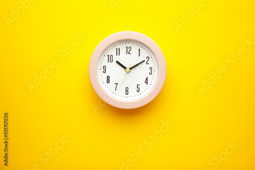 Pink clock on yellow background. Top view.