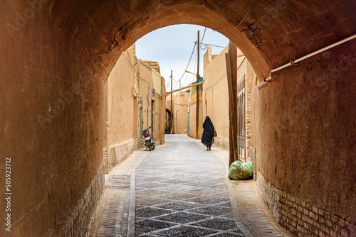 Photos Iranian woman wearing black chador walking along street of Yazd