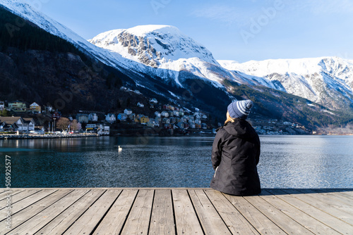 person on the pier with a lake and snowy mountains in the background. woman in the deck looking for a lake and snowy mountains landscape in Aurlandsfjord - Norway photo