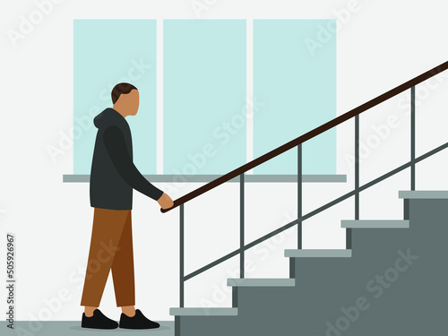 A male character stands near the stairs and holds on to the railing against the background of a wall with a window