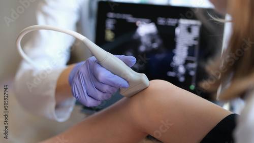 Doctor conducting ultrasound examination of knee joint in child closeup photo