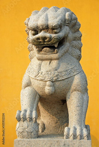 Zhenjiang, Jiangsu Province, China: A traditional Chinese lion statue against a yellow background at Dinghui Temple in Zhenjiang. photo