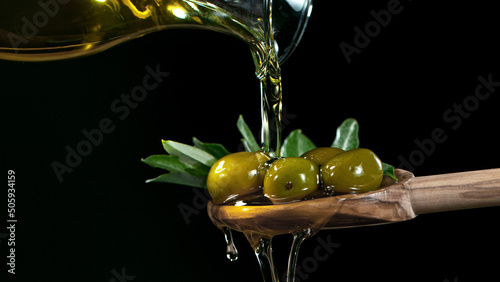 Macro shot of pouring olive oil on green olives.