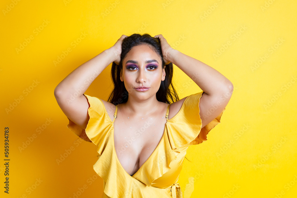 Φωτογραφία portrait of elegant and sensual hispanic young woman holding her hair in yellow
