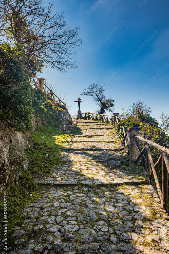 The small village of Tolfa, in Lazio. The cobblestone alley that climbs steeply to the Sanctuary of the Madonna della Rocca. The route is marked by the stations of the cross.