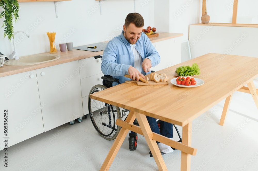 man in a wheelchair cuts vegetables in the kitchen man in a wheelchair cuts vegetables in the kitchen