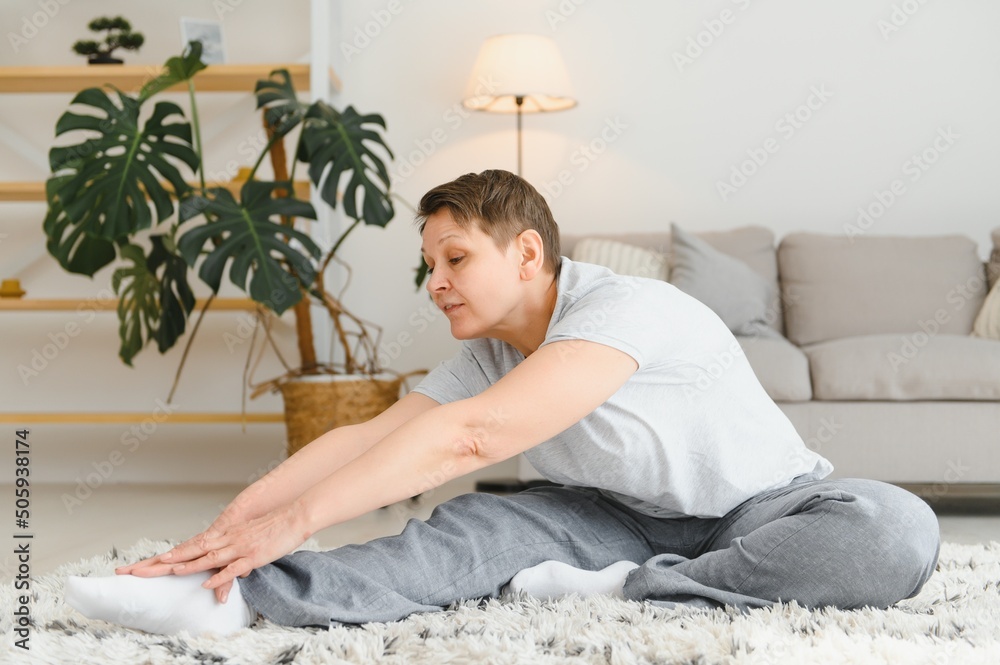 Middle age woman smiling happy doing exercise and stretching at home