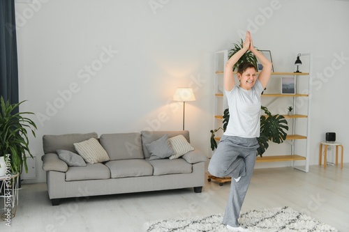 Middle age woman smiling happy doing exercise and stretching at home © Serhii