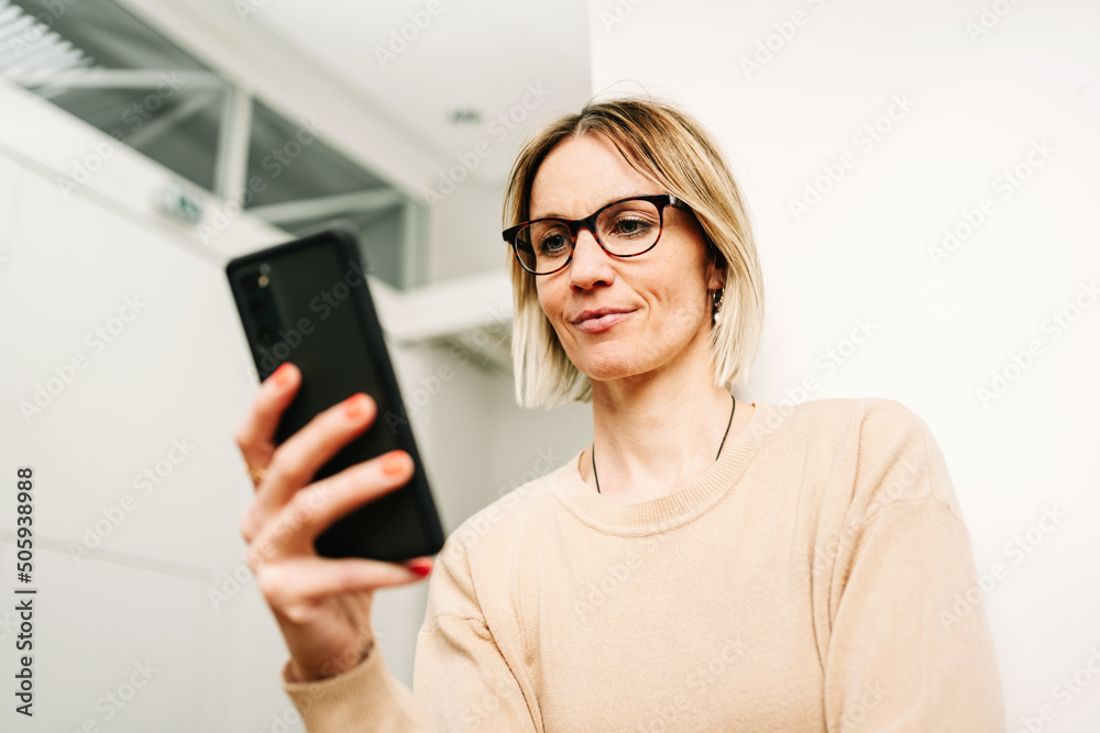 Business woman standing in office and looking at cell phone