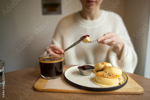 young woman eats delicious cheesecakes in a cafe and drinks coffee