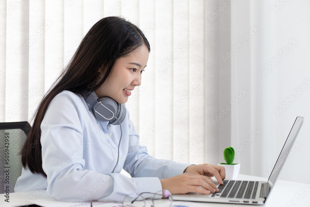 Asian woman is studying online via the internet with a cheerful smile, stay home, New normal, Covid-19 coronavirus, Social distancing, Internet learning.