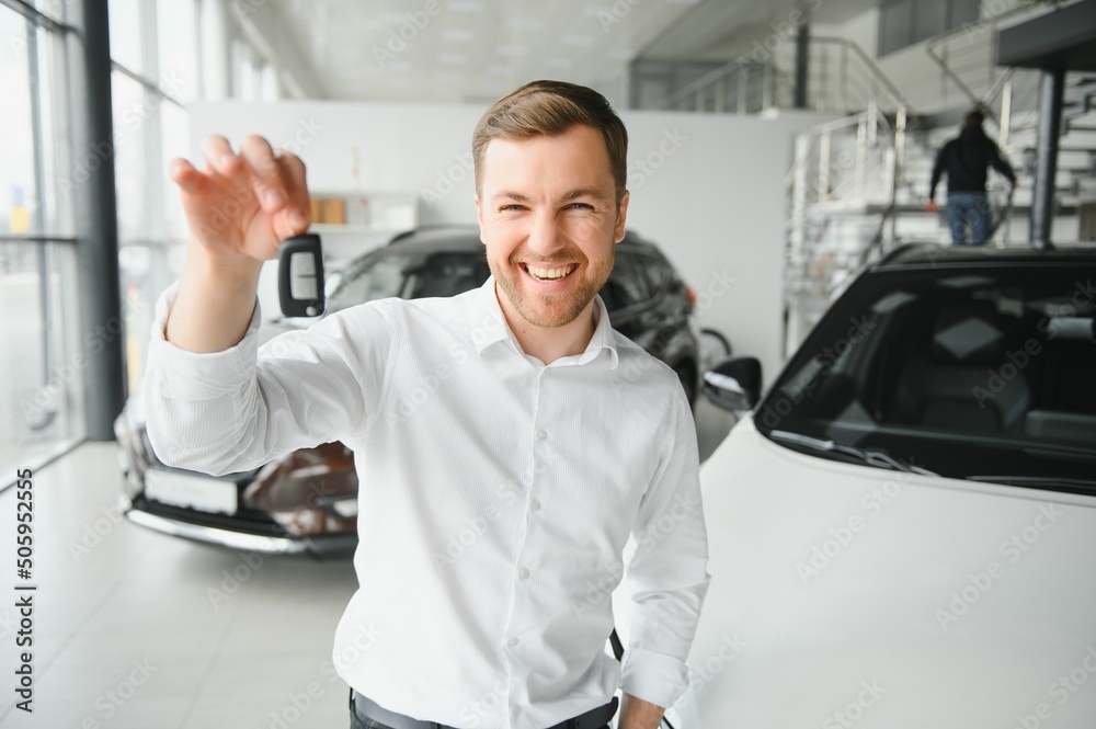 Happy man showing the key of his new car. Happy man showing the key of his new car.